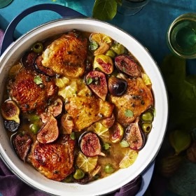 Ein köstliches Hähnchengericht mit Feigen, Oliven und Zitrusfrüchten in einer weißen Schüssel, ideal für das Abendessen.